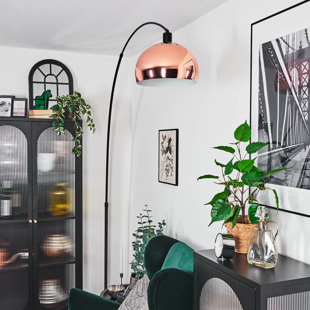 Ein modernes Wohnzimmer mit einer Kupferlampe, einem schwarzen Schrank, einem grünen Samtstuhl und einem Brückenfoto.