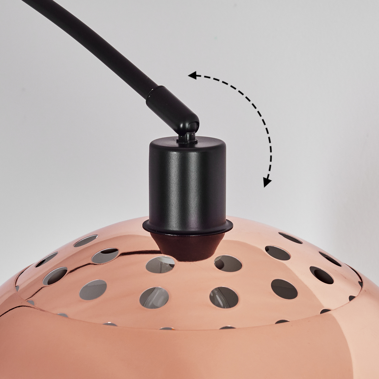 Nahaufnahme einer Kupferlampe mit schwarzem Arm und Halterung. Die Lampe hat viele runde Löcher. Der Arm kann schwenken. Weißer Hintergrund.
