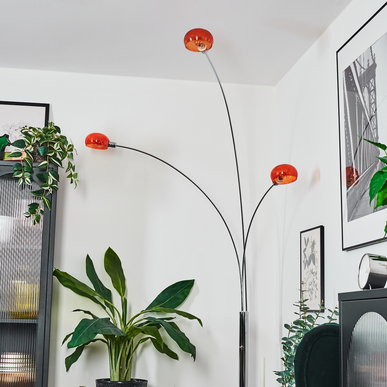 Eine moderne Stehlampe mit drei orangefarbenen Kugeln, Pflanzen und Kunst in einem Wohnzimmer.