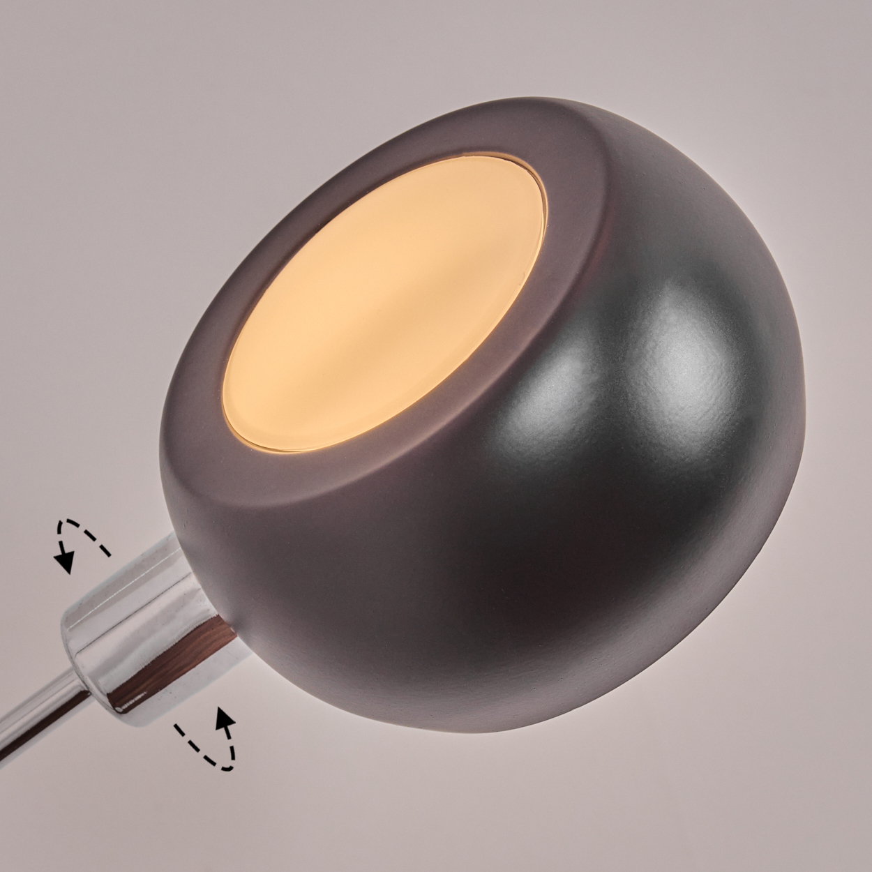 Nahaufnahme einer modernen Lampe. Die Lampe hat einen dunkelgrauen, runden Schirm mit leuchtender Oberfläche. Der Sockel ist verchromt.