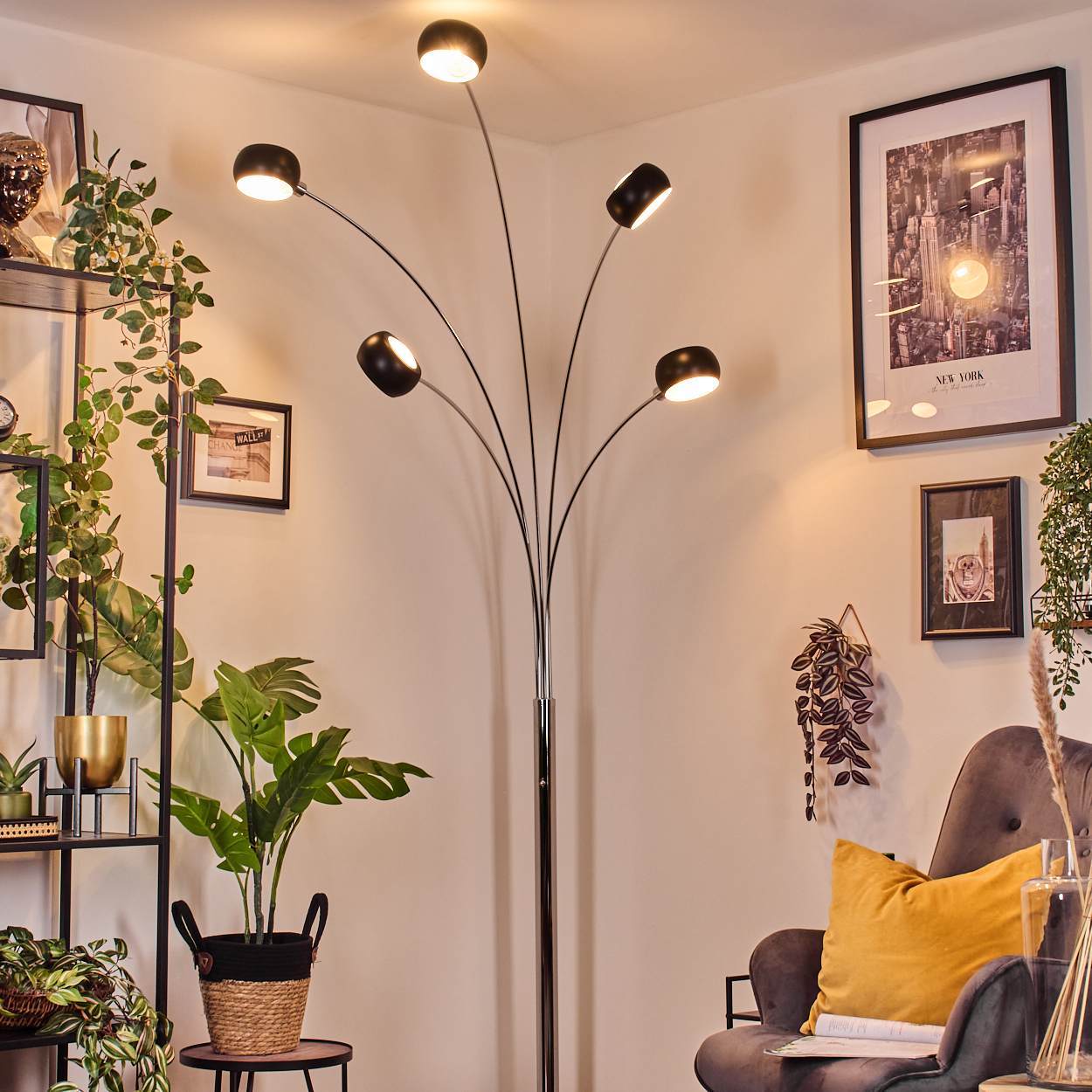 Ein modernes Wohnzimmer mit einer schwarzen Bogenlampe, Pflanzen, einem gerahmten New York-Poster und einem grauen Sessel.