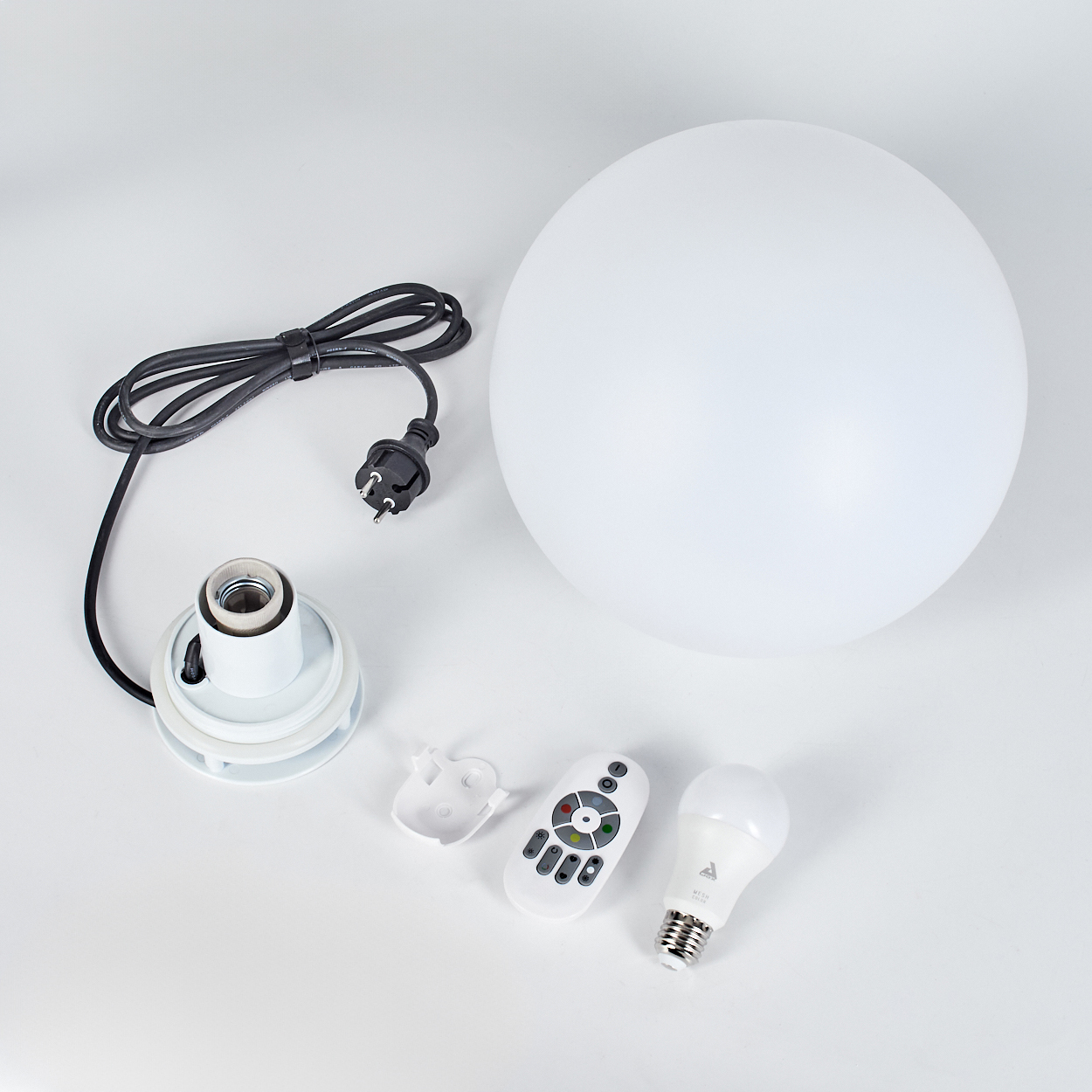 Ein zerlegtes weißes Kugelleuchten-Set mit Glühbirne, Fernbedienung und Komponenten auf weißer Oberfläche. Ein schwarzes Netzkabel und Stecker sind sichtbar.
