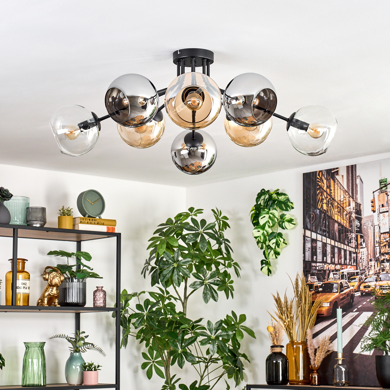 Moderne Deckenleuchte mit Glaskugeln. Pflanzen, Regale mit Dekoration und ein Stadtbildgemälde vervollständigen den stilvollen Innenraum.