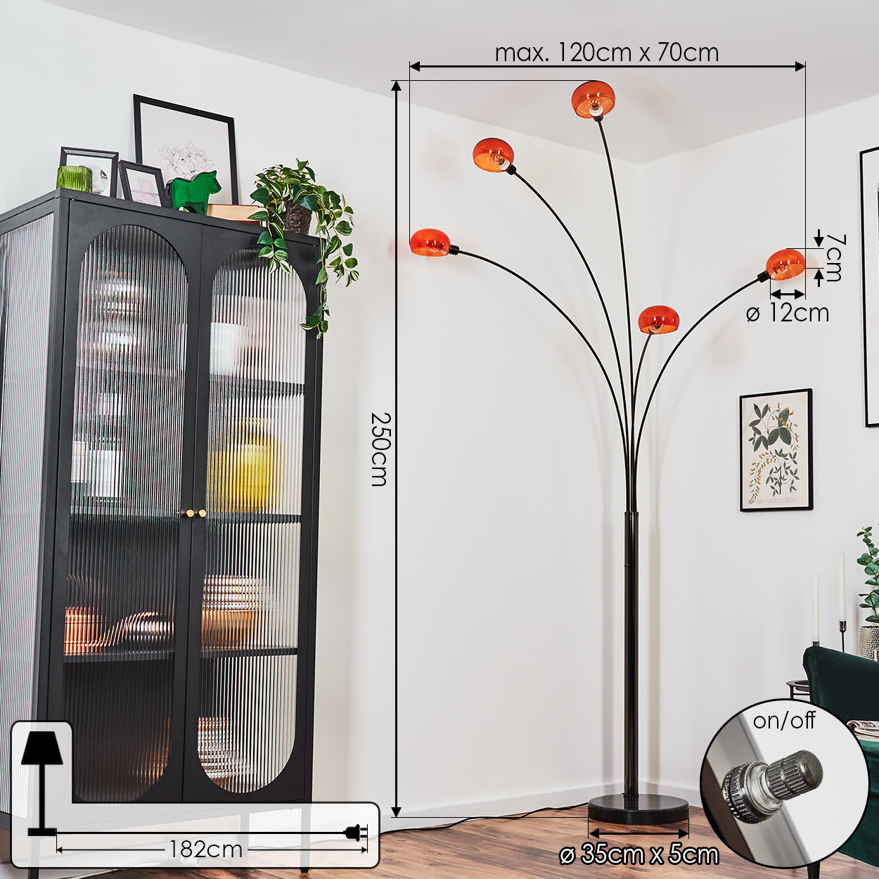 Eine moderne schwarze Stehlampe mit fünf orangefarbenen Lampenschirmen. Ein schwarzer Schrank und grüne Pflanzen im Hintergrund.