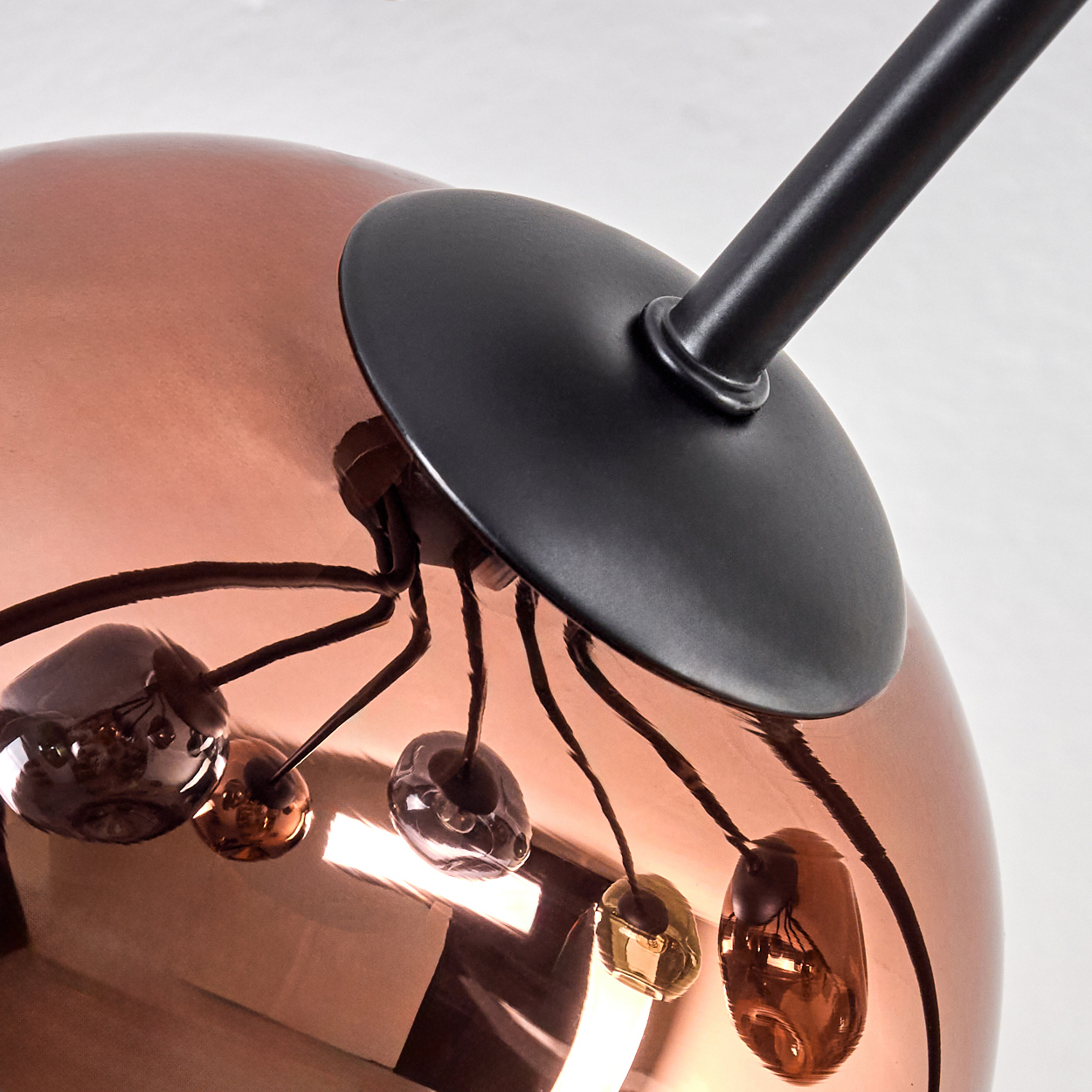 Nahaufnahme einer modernen Lampe. Sie hat eine kupferfarbene Kugel mit schwarzen Akzenten und mehrere kleine Glaskugeln.