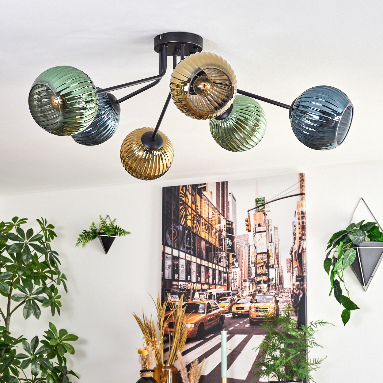 Deckenlampe mit Glaskugeln, Gemälde von NYC, Pflanzen in Töpfen und eine Vase mit dekorativen Elementen.