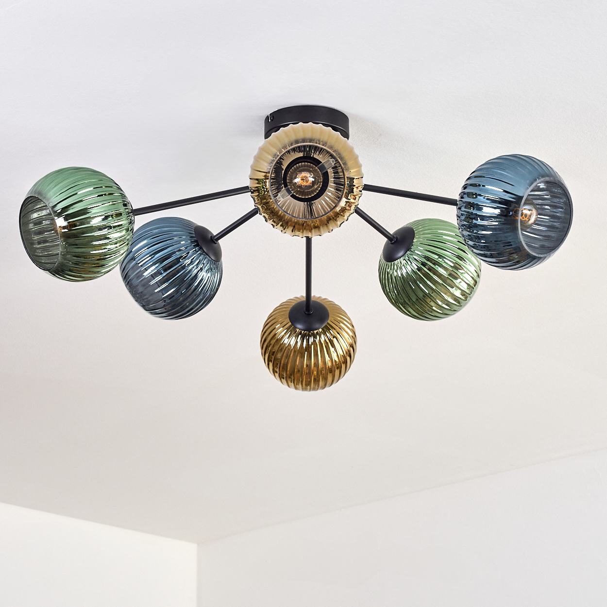 Eine moderne Deckenleuchte mit sechs Glaskugeln in Grün-, Blau- und Goldtönen. Sie hat einen schwarzen Metallrahmen, montiert an einer weißen Decke.