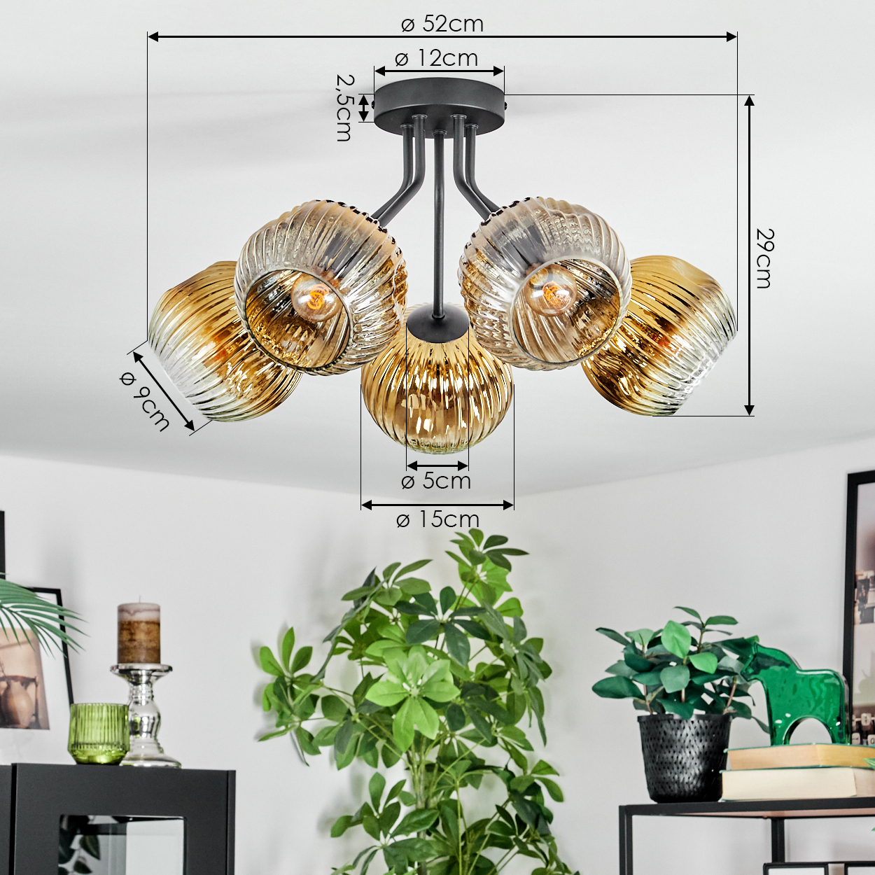 Deckenlampe mit fünf Glaskugeln, Maße beschriftet. Unten ein Tisch mit Pflanzen, Kerze und anderen Dekorationen.