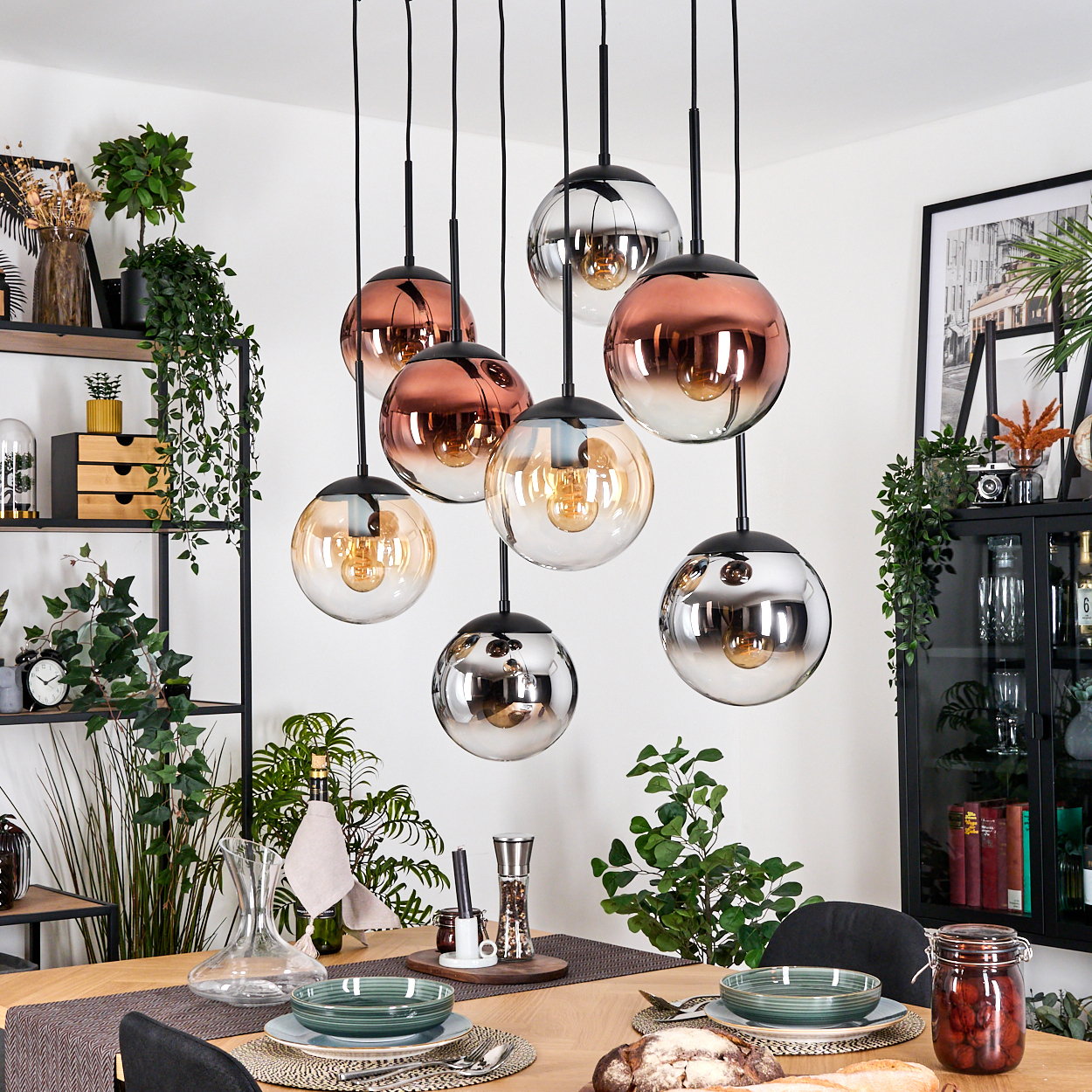 Esszimmer mit Pendelleuchten. Tisch mit Tellern, Besteck, Brot und Glas. Pflanzen und Regale mit Dekoration.