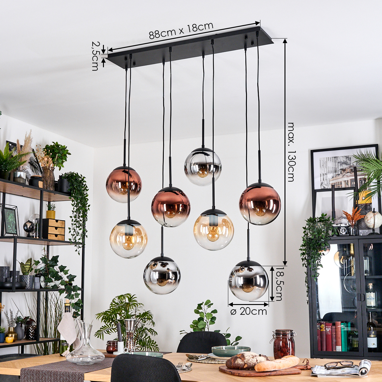 Ein modernes Esszimmer mit Hängelampen, einem Holztisch und Pflanzen. Die Lampen haben Glaskugeln in Metallicfarben.