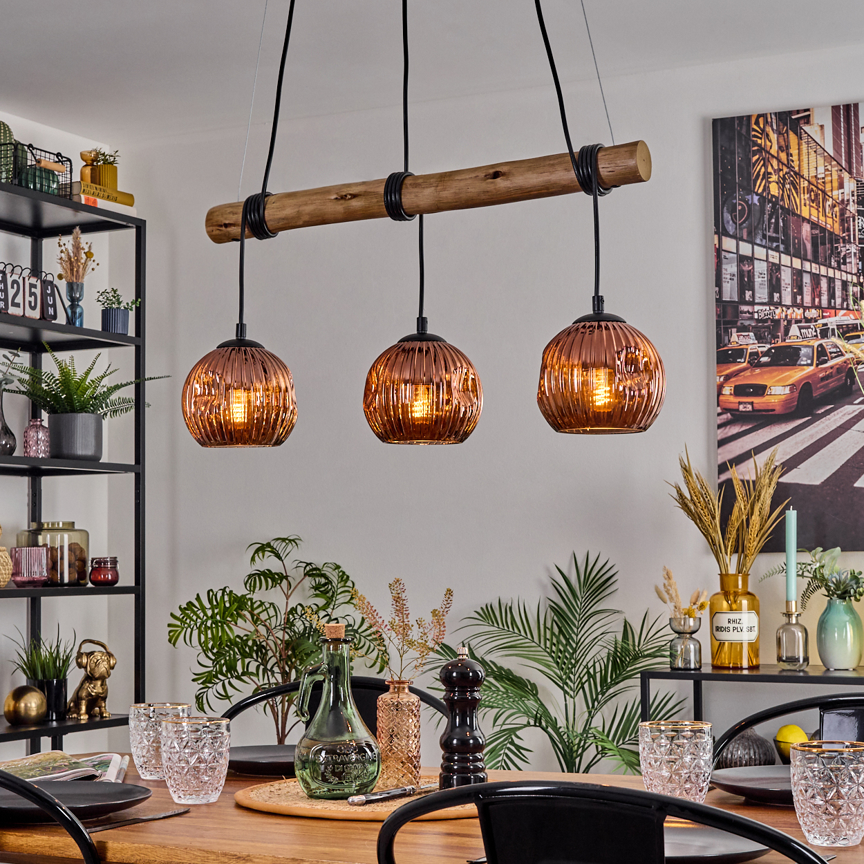 Esszimmer mit Holztisch für ein Essen, mit Hängelampen und dekorativen Gegenständen sowie einem Stadtbildgemälde.