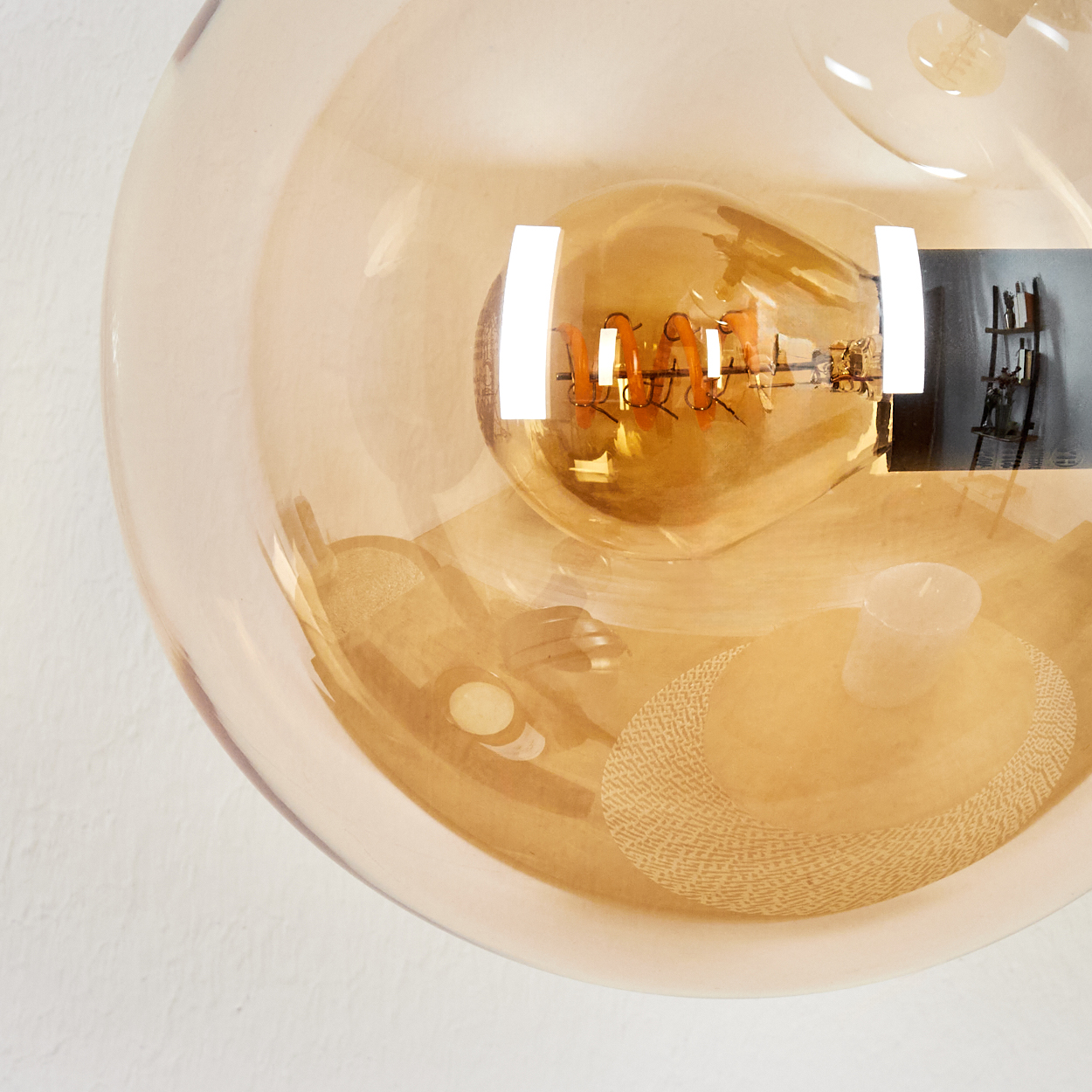 Nahaufnahme einer Glaskugel mit einer Glühbirne im Inneren. Eine Kerze und ein dekoratives Element sind ebenfalls in der Kugel zu sehen.
