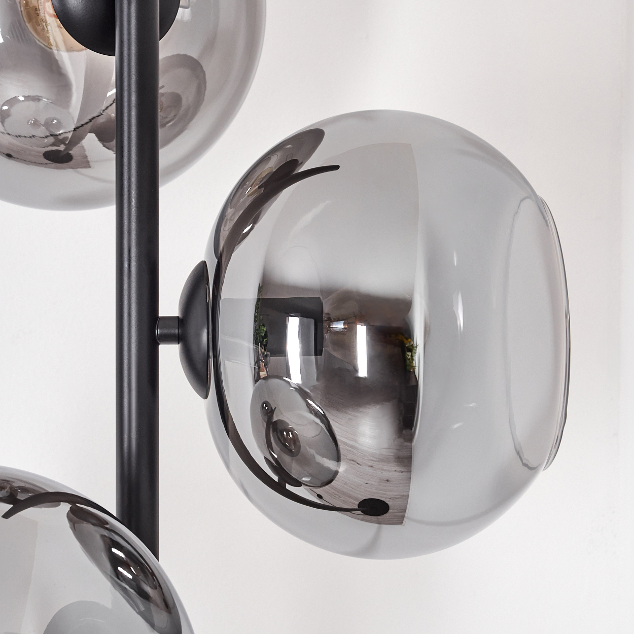 Nahaufnahme einer modernen Lampe mit grauen Glaskugeln. Schwarzer Metallrahmen trägt die Kugeln. Reflexionen sind sichtbar.