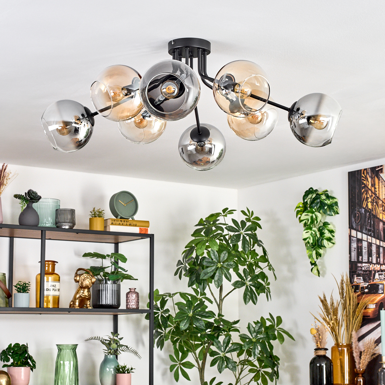 Eine moderne Deckenlampe mit Glaskugeln, Pflanzen und einem Regal mit Dekoration. Die Lampe hat schwarze Arme mit transparenten und verspiegelten Kugeln.