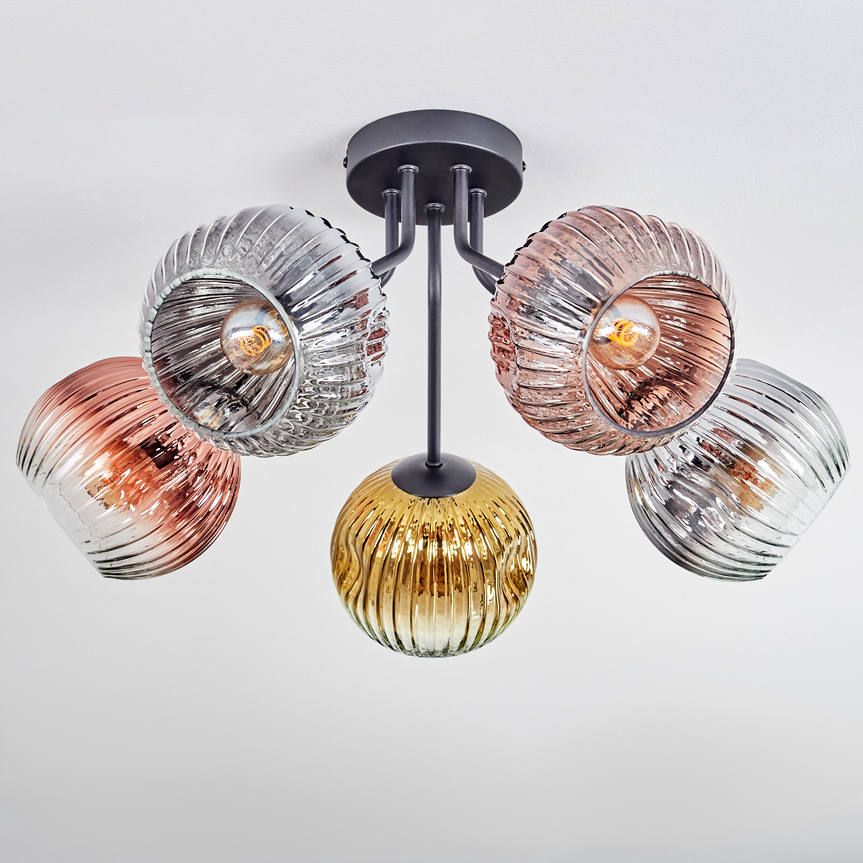 Deckenleuchte mit fünf Glaskugeln in Silber, Rosé und Gold. Schwarzer Metallrahmen. Glühbirnen sind in den Kugeln sichtbar.