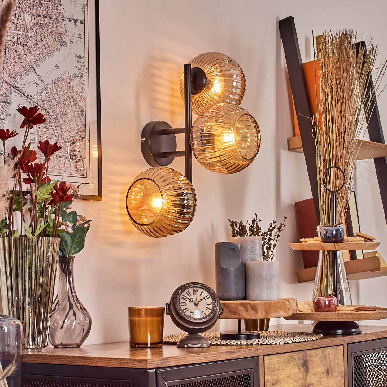 Innenraum mit Wandlampe, Uhr, Vasen und Karte. Enthält Blumen, Kerzen und eine Leiter mit Deko.