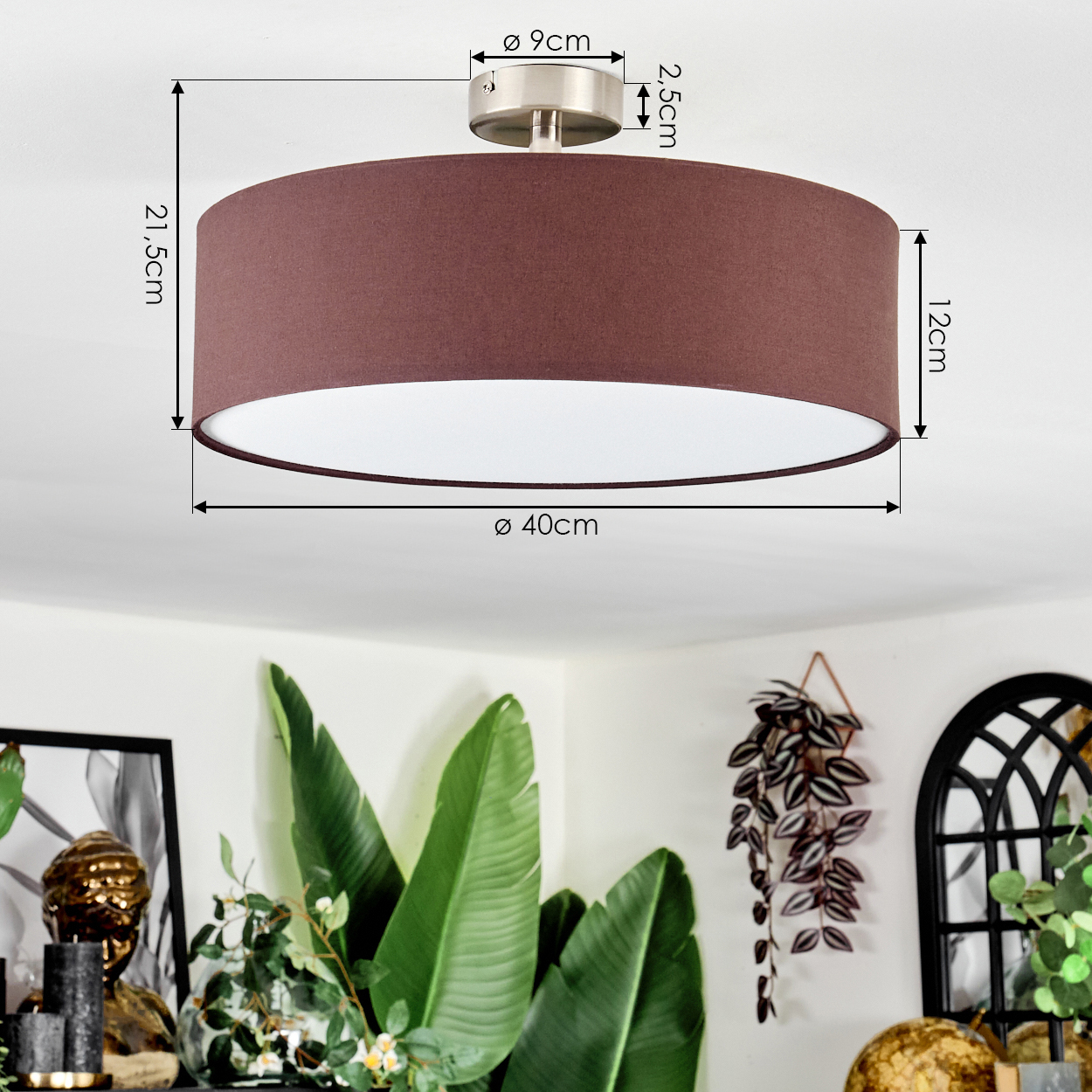 Eine braune Deckenlampe mit Maßen ist installiert. Pflanzen und Dekorationen sind im Hintergrund.