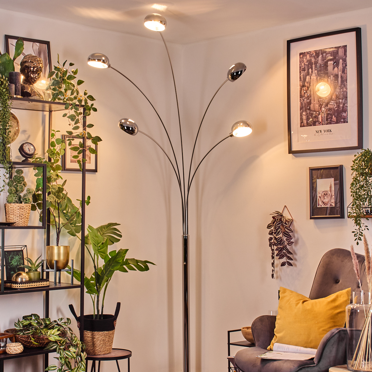 Ein modernes Wohnzimmer mit Stehlampe, Pflanzen und einem gerahmten Bild. Ein grauer Sessel mit gelbem Kissen ist sichtbar.