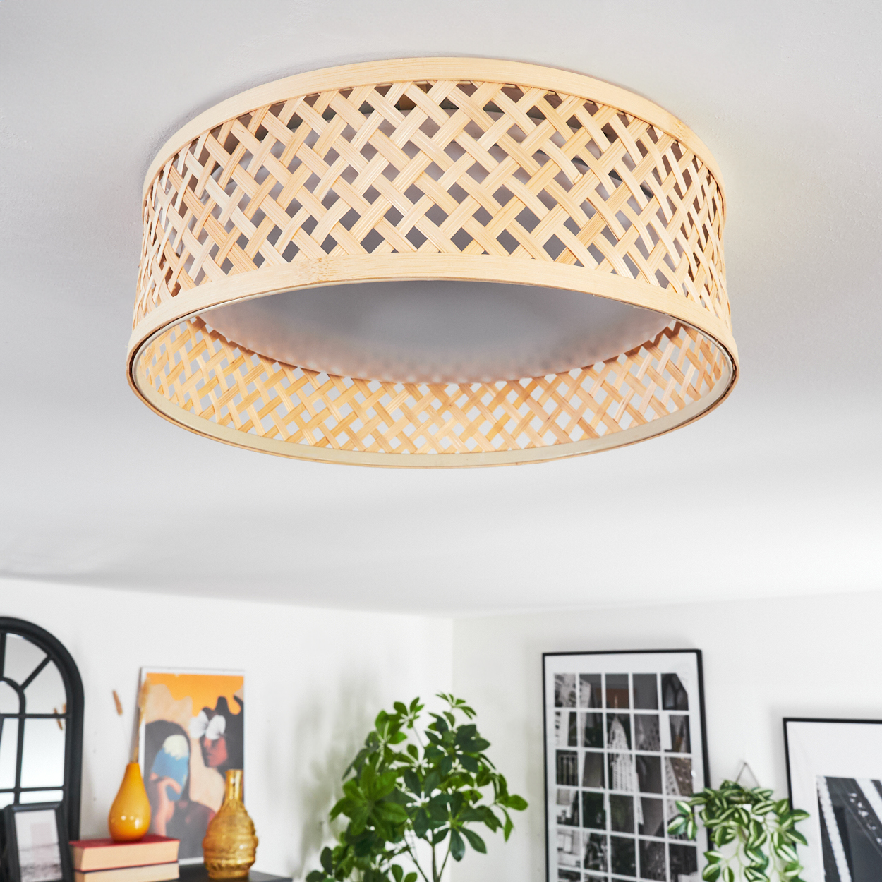 Wicker-Lampenschirm an der Decke. Darunter sind Kunst und Pflanzen zu sehen. Der Lampenschirm hat ein gewebtes Muster.