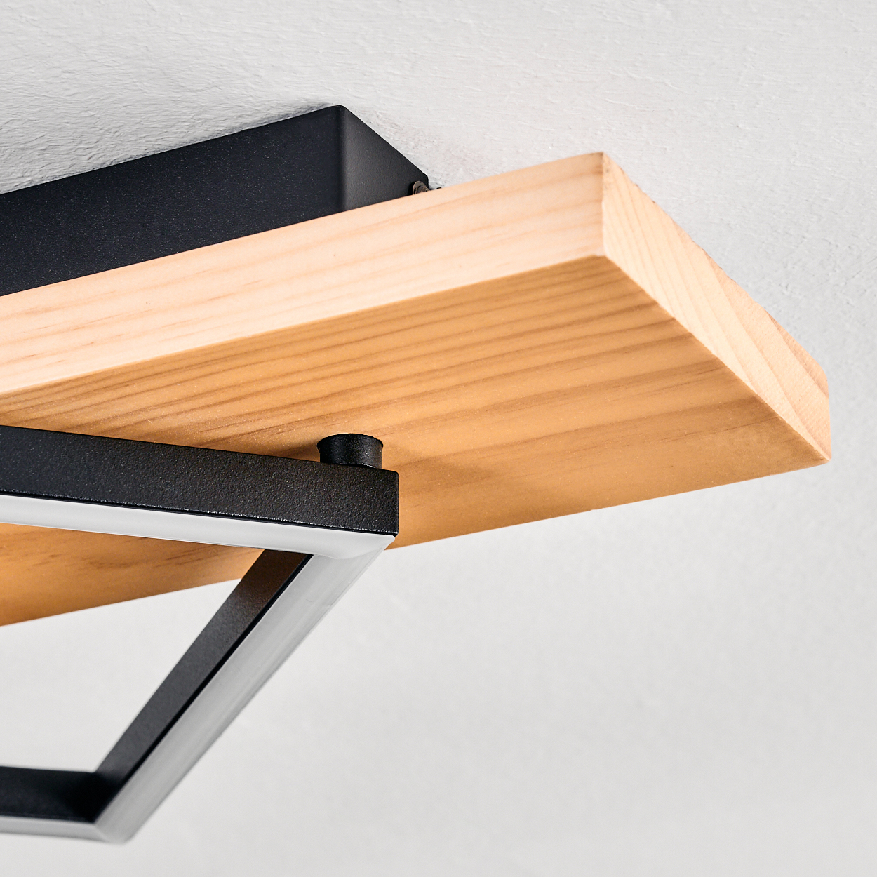 Nahaufnahme eines Holzregals mit schwarzen Metallstützen. Das Regal ist hellbraun und an einer weißen Wand befestigt. Metallrahmen quadratisch.