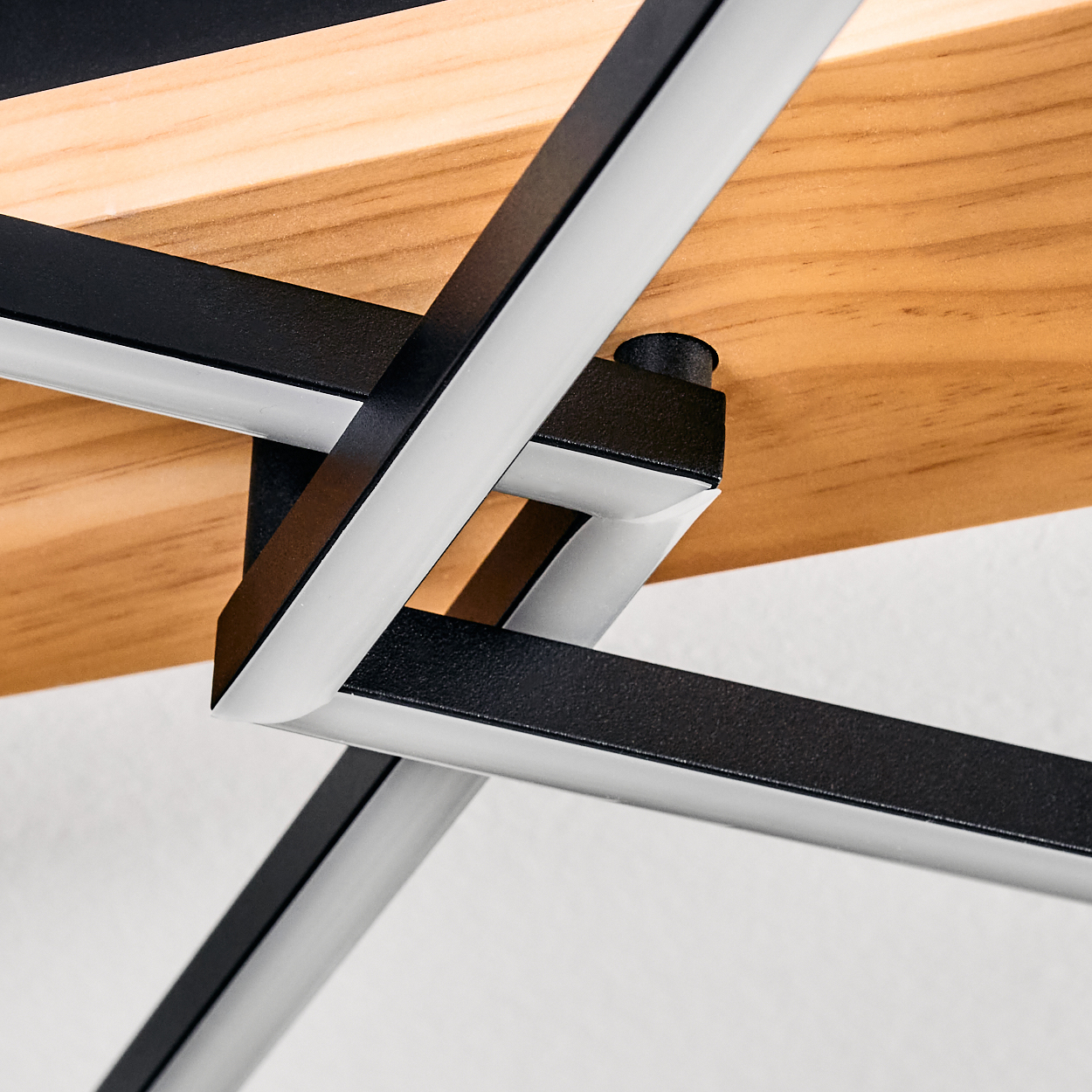 Nahaufnahme eines Holzregals mit schwarzen Metallstützen. Das Holz hat eine natürliche Maserung. Das Metall hat weiße und schwarze Teile.