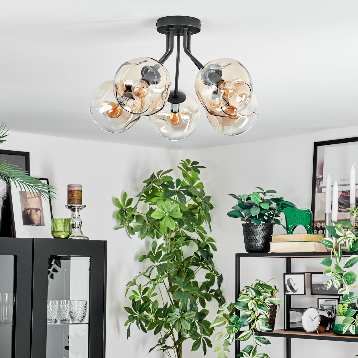 Ein modernes Wohnzimmer mit einer einzigartigen Leuchte, Pflanzen und dekorativen Gegenständen auf Regalen und einem Schrank.