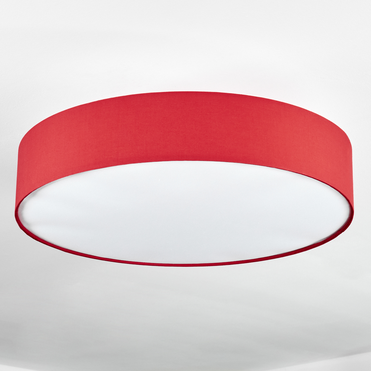 Ein roter Lampenschirm ist an einer weißen Decke befestigt. Der Lampenschirm hat eine zylindrische Form, und sein innerer Teil ist weiß.