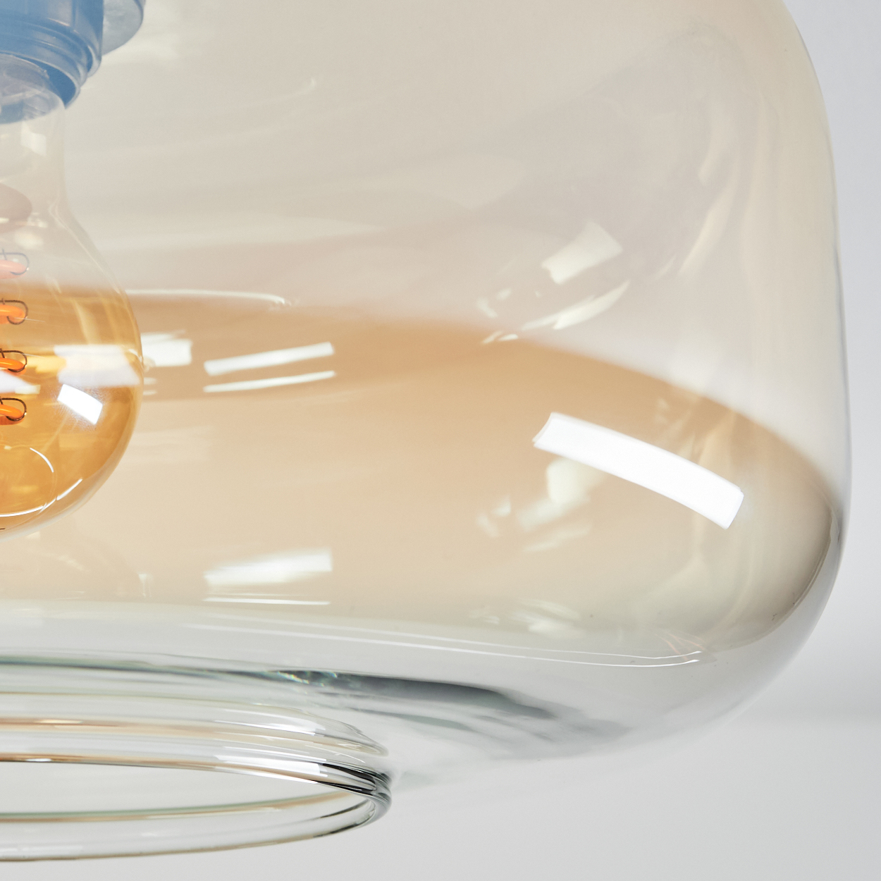 Nahaufnahme eines transparenten Glasbehälters mit glockenförmiger Form. Das Glas hat eine Farbverlauf, hellbraun bis klar. Weißer Hintergrund.