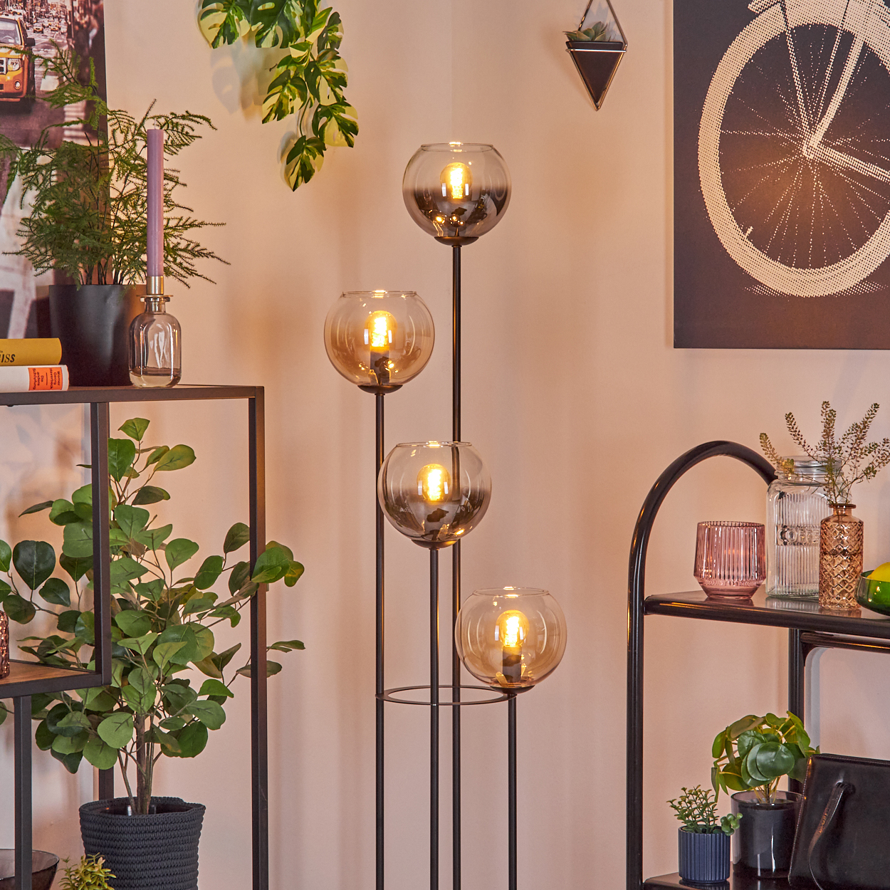 Modernes Wohnzimmer mit Stehlampe mit vier Glaskugeln, Pflanzen und Dekorationsgegenständen auf Regalen.