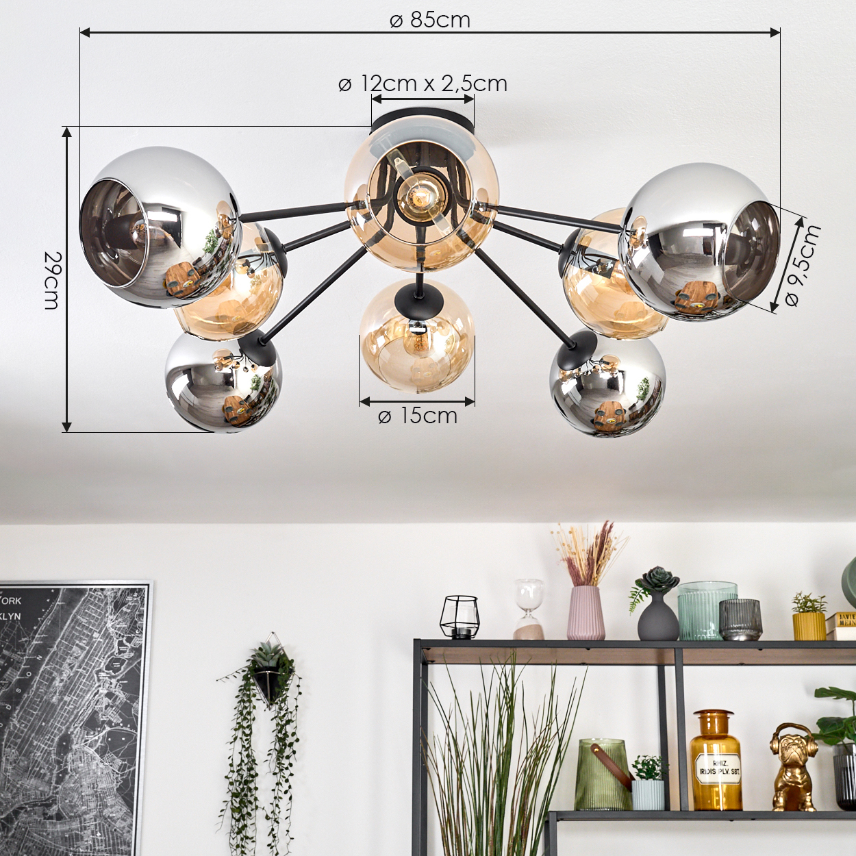 Eine moderne Deckenlampe mit mehreren kugelförmigen Lichtern. Abmessungen sind angegeben. Darunter Regale mit Dekoration und Pflanzen. Eine Karte hängt an der Wand.