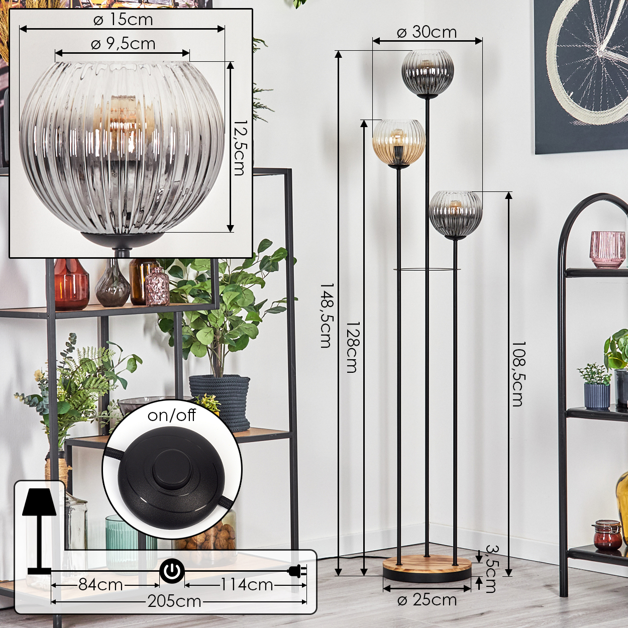 Eine Stehlampe mit drei Glasschirmen, einem schwarzen Metallrahmen und einem Holzsockel. Die Lampe steht in der Nähe von Regalen mit Pflanzen und Dekoration.