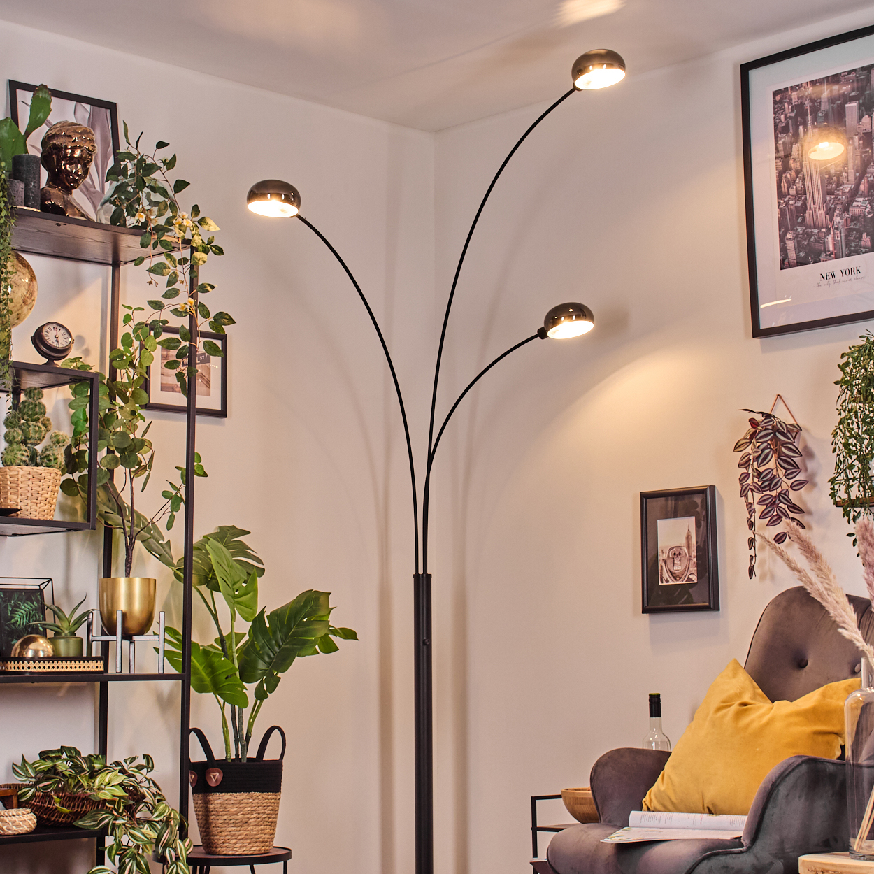 Ein modernes Wohnzimmer mit schwarzer Stehlampe, Pflanzen, einem gerahmten Bild, einem Stuhl und einem Regal.