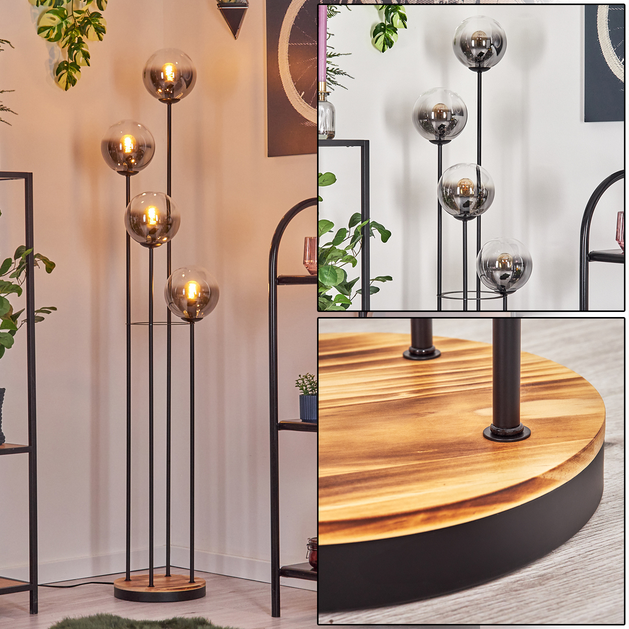 Eine moderne Stehlampe mit vier Glaskugeln. Sie steht auf einem Holzsockel mit schwarzem Metallrahmen. Regale und Pflanzen im Hintergrund.