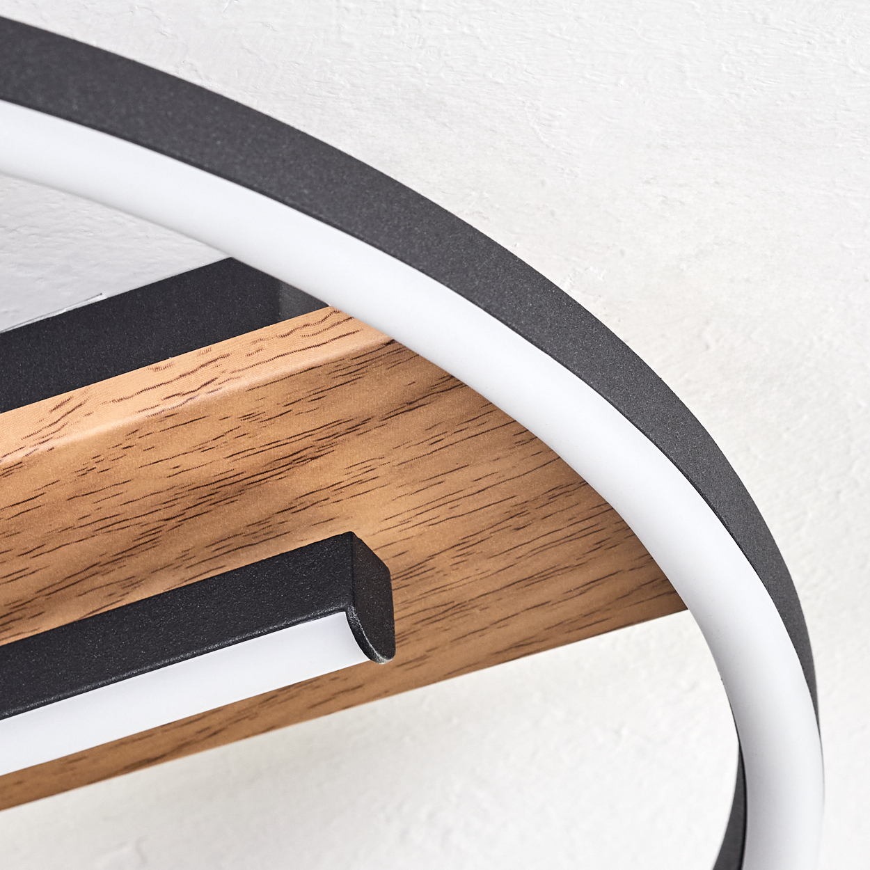 Nahaufnahme einer modernen Leuchte. Sie hat ein kreisförmiges Design mit Holzsockel, schwarzen Akzenten und weißem Licht.
