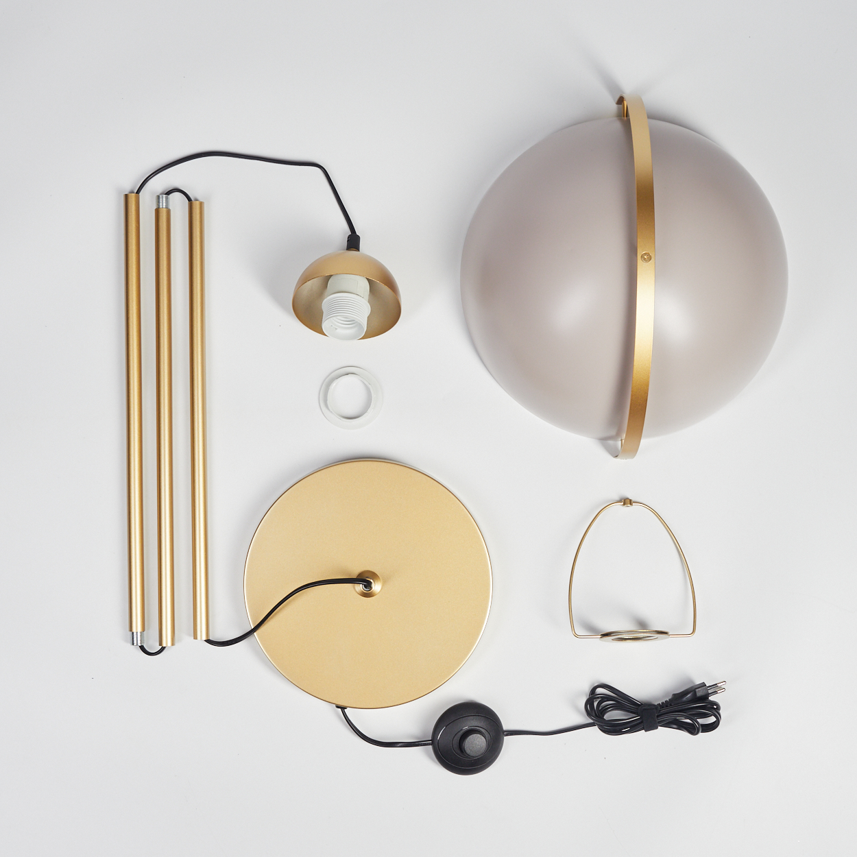 Eine zerlegte Stehlampe. Zu den Teilen gehören goldene Stangen, ein Lampenschirm, ein Sockel, ein Glühbirnenhalter und ein Fußschalter auf weißem Untergrund.