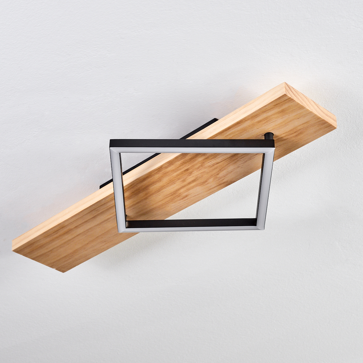 Moderne Deckenleuchte. Sie hat ein Holzbrett, eine schwarze Metallstütze und eine quadratische Leuchte mit weißem Schein.