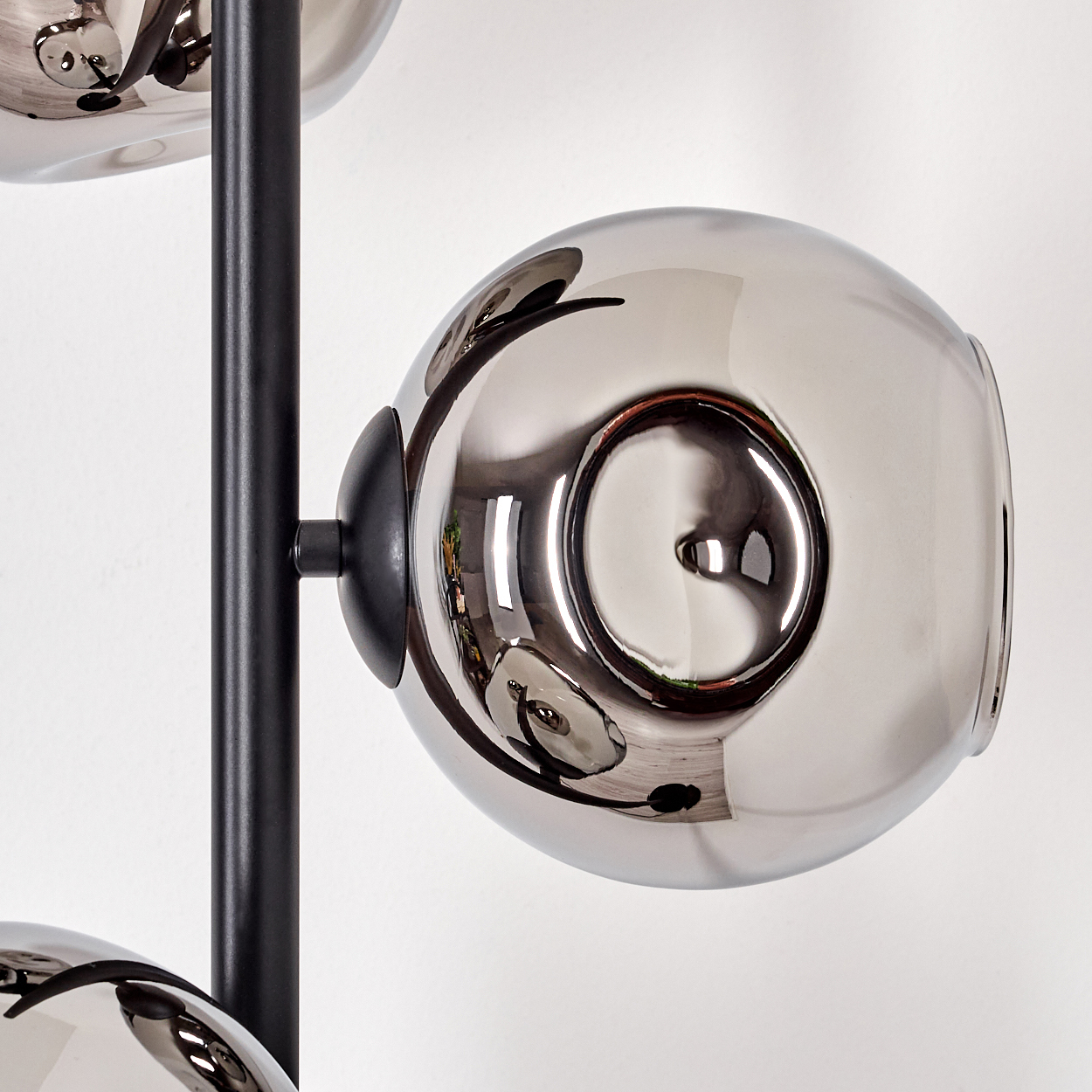 Nahaufnahme einer modernen Lampe. Kugelförmige, reflektierende Schirme sind an einer schwarzen Metallsäule befestigt.