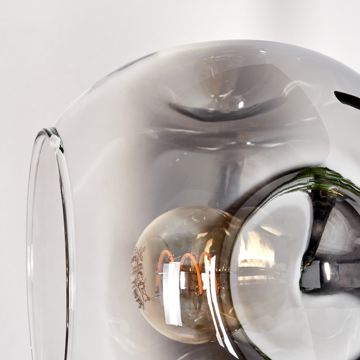Nahaufnahme einer modernen Lampe. Sie hat ein großes, klares Glas mit einer Glühbirne. Die Glühbirne hat einen orangefarbenen Faden.