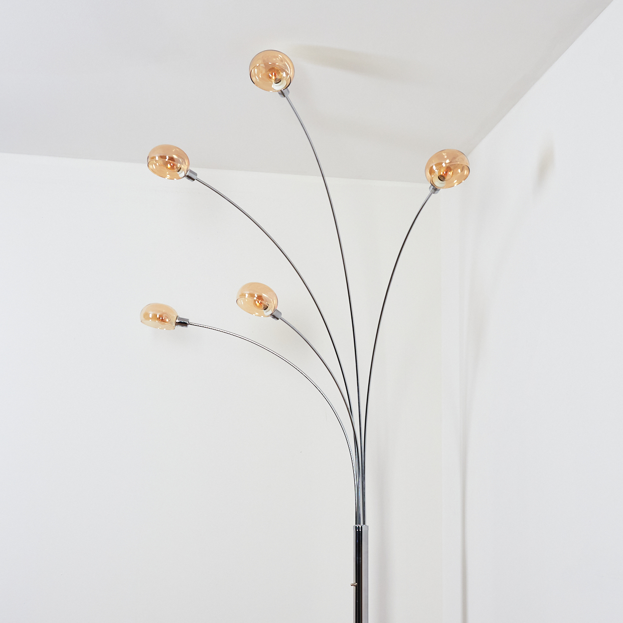 Eine moderne Stehlampe mit fünf kugelförmigen, bernsteinfarbenen Lichtern, die sich von einem Chromständer erstrecken.