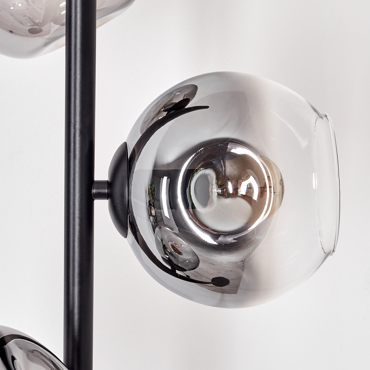 Moderne Lampe mit Glaskugeln, die die Umgebung reflektieren. Schwarze Metallstruktur vor weißem Hintergrund.