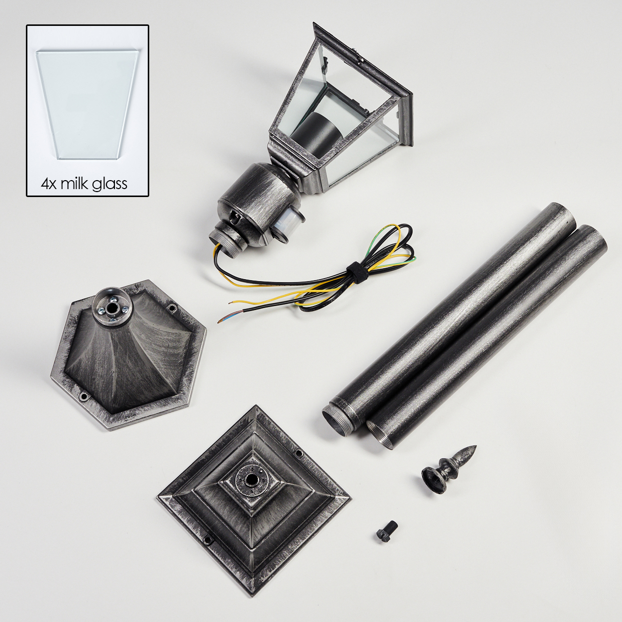 Zerlegte Teile einer Außenlampe: Milchglas, Lampenkopf, Stangen, Sockel, Schrauben und Zierelemente auf weißem Untergrund.