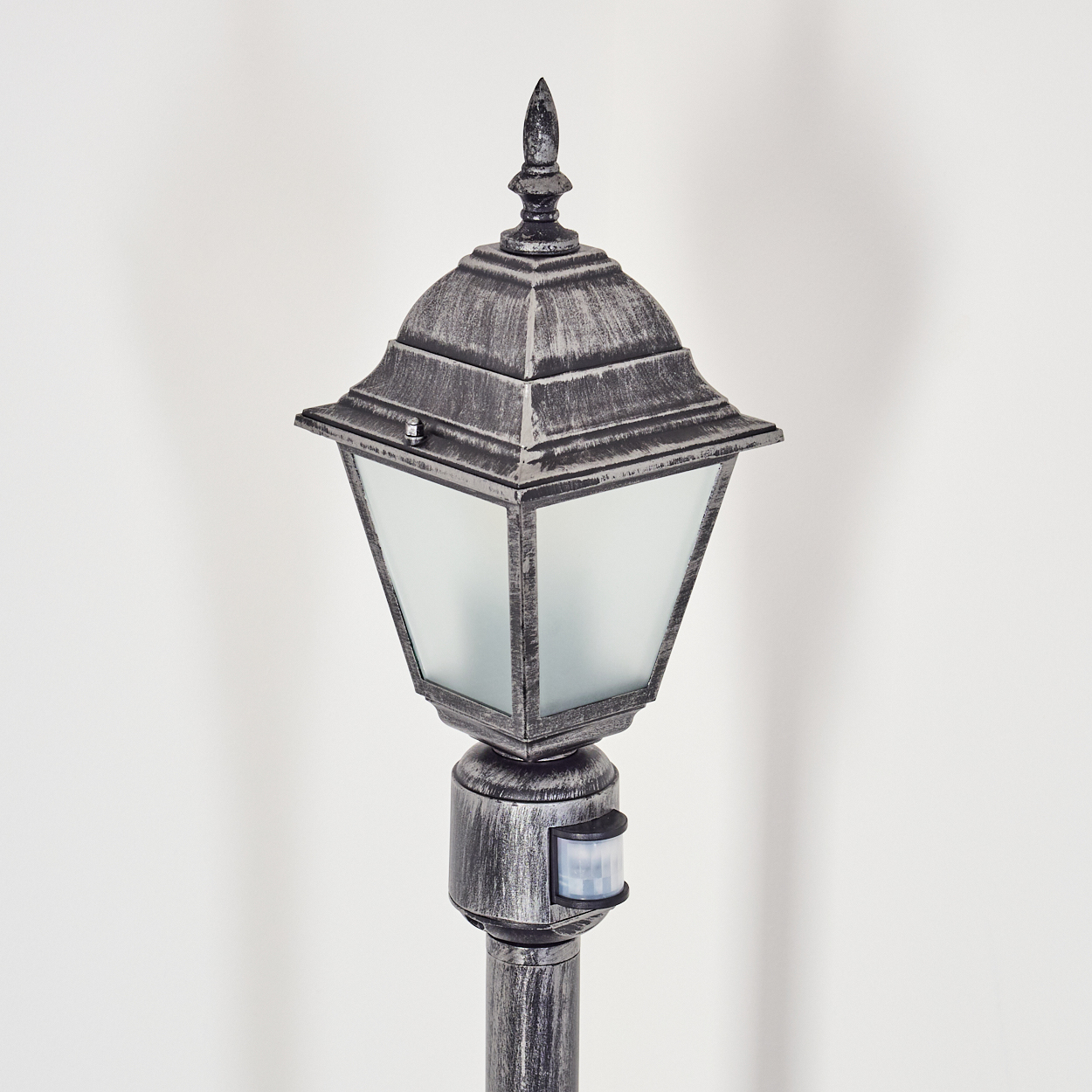 Dekorative Außenlaterne. Sie hat ein metallisches Finish und eine Glasscheibe. Der Hintergrund ist weiß.