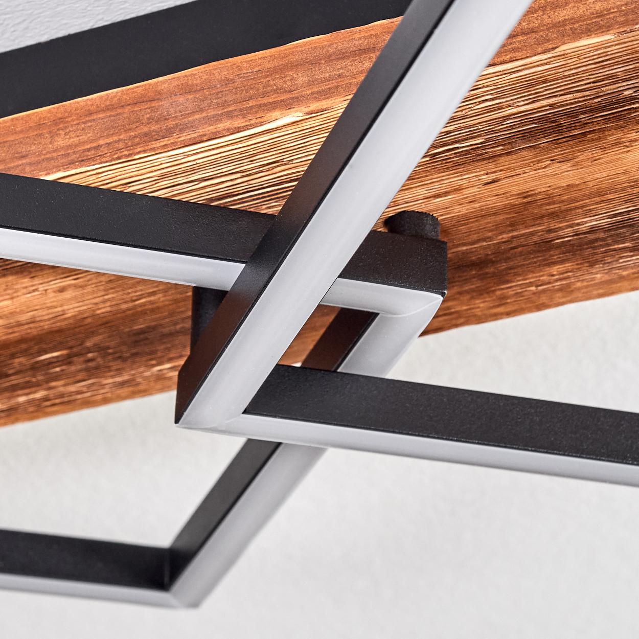 Geometrische moderne Lampe. Schwarzer Metallrahmen mit integriertem weißem Licht und Holzpaneel-Hintergrund.