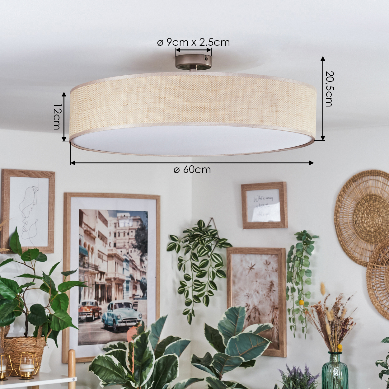 Ein beiger Lampenschirm mit Maßen ist an der Decke montiert. Darunter dekorieren gerahmte Bilder und Pflanzen die weiße Wand, was eine gemütliche Atmosphäre schafft.