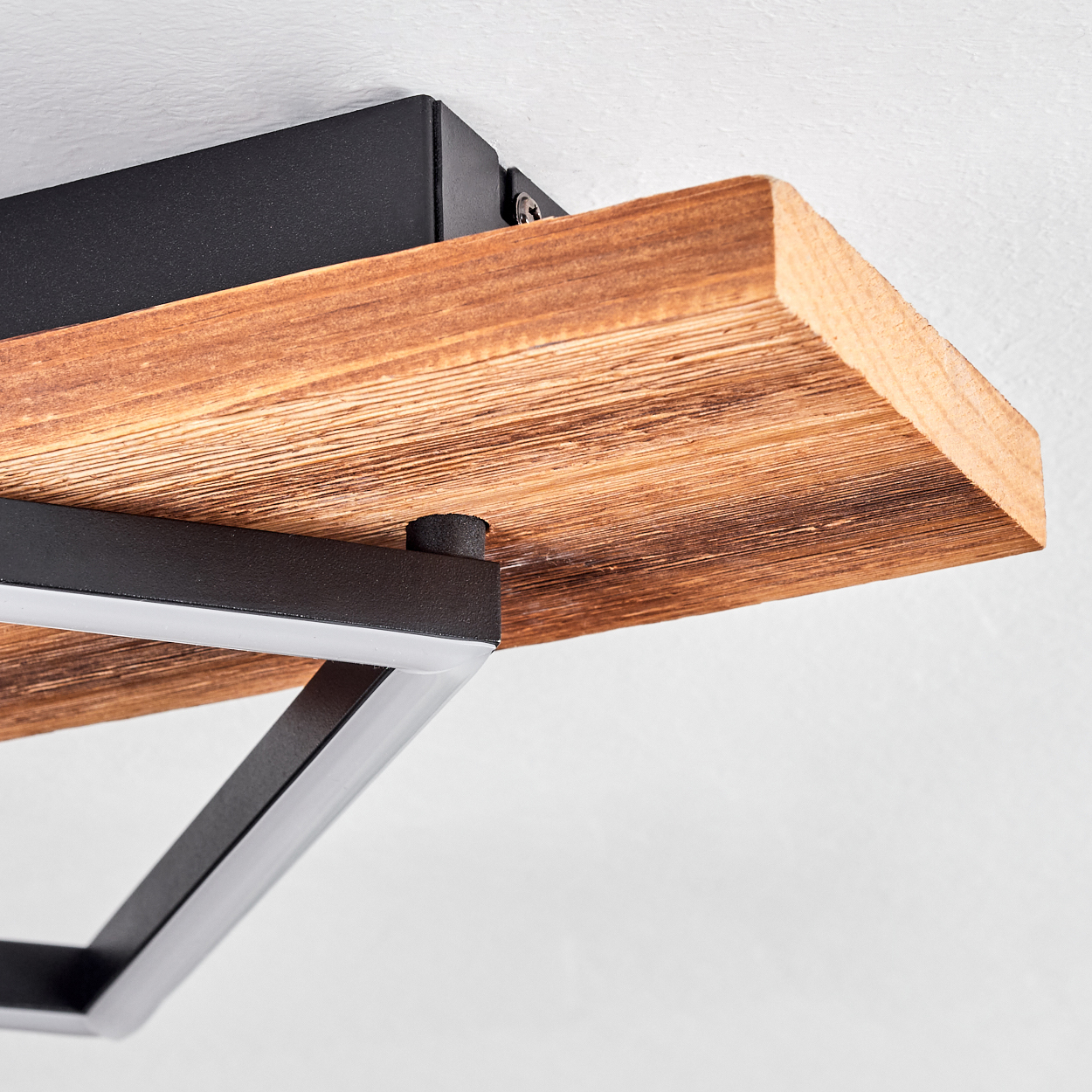 Nahaufnahme eines Holzregals mit schwarzem Metallrahmen. Das Regal ist an einer weißen Wand befestigt. Das Holz zeigt Maserungsdetails.