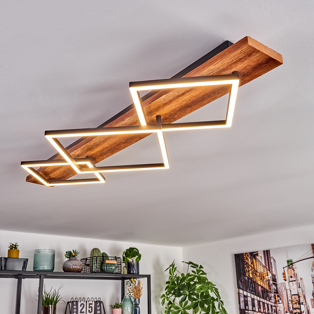 Moderne Deckenleuchte mit geometrischem Design. Holz- und Schwarzelemente, mit rechteckigen Leuchten. Pflanzen und Deko darunter.