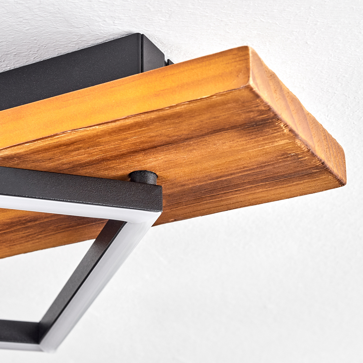 Nahaufnahme eines Holzregals, das an einer weißen Decke befestigt ist. Das Regal ist braun und wird von schwarzem Metall getragen. Ein weißes Licht ist sichtbar.
