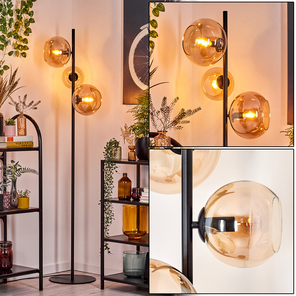 Eine moderne Stehlampe mit drei bernsteinfarbenen Glaskugeln. Schwarzer Metallrahmen. Regale mit Deko und Pflanzen im Hintergrund.