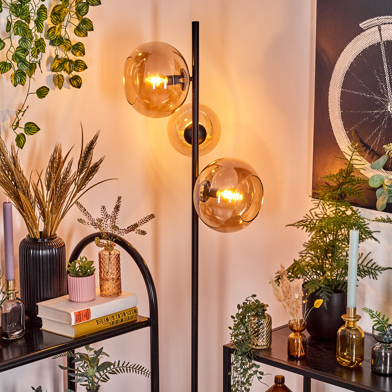 Eine moderne Zimmerecke mit einer dreifachen Glühbirnenlampe, Pflanzen, Vasen, Büchern und Kunstwerken. Farben: Schwarz, Braun, Grün und Gold.