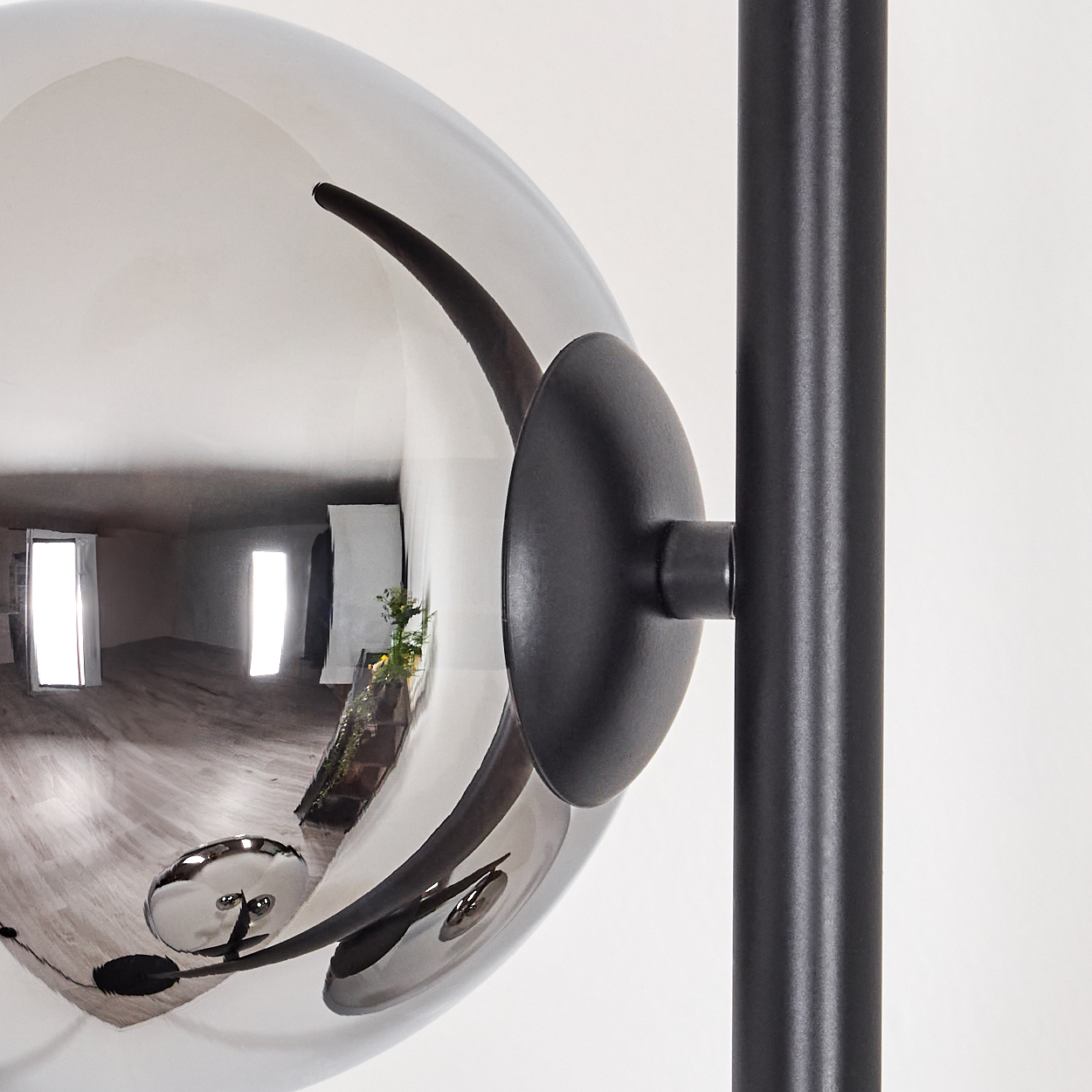 Nahaufnahme einer modernen Lampe. Die Lampe hat eine reflektierende Kugel, einen schwarzen Stiel und eine runde schwarze Halterung.